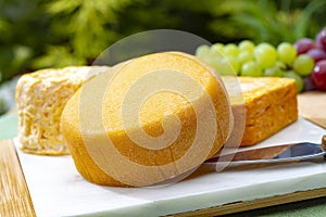 French cheeses collection, yellow Riche de Saveurs and Le peche des bons peres cheeses served on white marble plate outdoor in