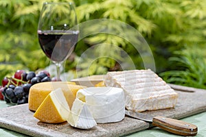 French cheeses collection, yellow Riche de Saveurs, Vieux Pane and Le peche des bons peres cheeses served with glass of red port