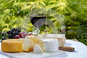 French cheeses collection, yellow Riche de Saveurs, Vieux Pane and Le peche des bons peres cheeses served with glass of red port