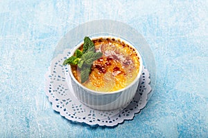 French Creme Brulee on the plate, traditional french vanilla cream dessert with caramelised sugar on top on a blue