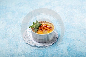 French Creme Brulee on the plate, traditional french vanilla cream dessert with caramelised sugar on top on a blue background