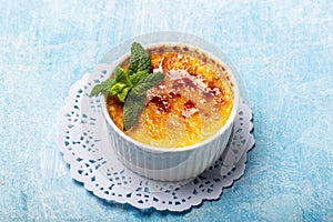 French Creme Brulee on the plate, traditional french vanilla cream dessert with caramelised sugar on top on a blue background