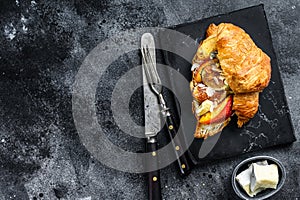 French croissant with bree cheese, peach and figs. Black wooden background. Top view. Copy space