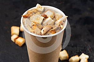 French cuisine hot food delivery - Close-up of mushroom soup with chicken meat in disposable paper cups on a dark stone