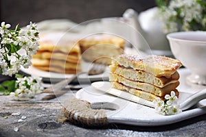 French cuisine. Matefaim. Stack of sweet Apple Pancakes, cup of tea and white spring flowers