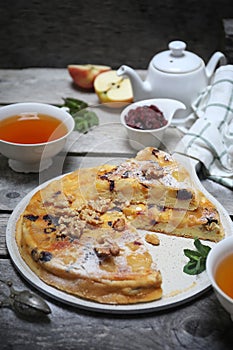 French cuisine. Matefaim. Sweet Apple Pancake with dried cranberries and walnuts, two cups of tea for breakfast