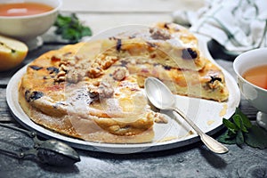 French cuisine. Matefaim. Sweet Apple Pancake with dried cranberries and walnuts, two cups of tea for breakfast