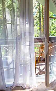 French doors open onto a balcony with a view of leafy green trees. nature. relax concept. vocations