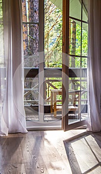 French doors open onto a balcony with a view of leafy green trees. nature. relax concept. vocations
