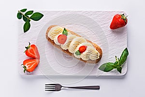 French eclair grazed with chocolate and fruity strawberry cream or sweet Italian profiteroles and fresh juicy strawberries, food