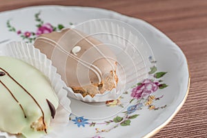 French eclairs on colorful porcelain plate on wooden table