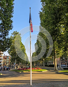 French flag on pole in scenic landscaped street in France