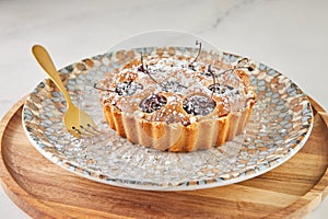 French Flair, cherry clafoutis presented on white marble with powdered sugar and fork