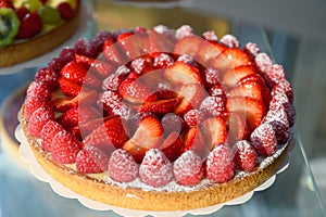 French fresh baked sweet pastry with fresh red summer fruits and berries in confectionery shop close up