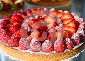 French fresh baked sweet pastry with fresh red summer fruits and berries in confectionery shop close up