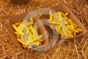 French fries in a cardboard plate on a hay table. chips. traditional country food at a farmer\'s festival