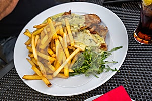 French fries with chicken meat, sauce and rucola leaf on plate