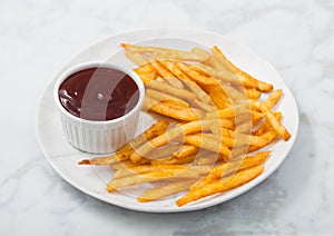 French fries chips with tomato ketchup in white plate on white marble background
