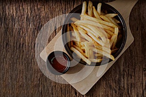French fries with ketchup on a dark wood.