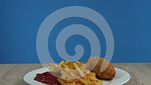 French fries with Kiev cutlet with red sauce appear on a blue background