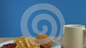 French fries with Kiev cutlet with red sauce appear on a blue background