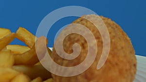 French fries with Kiev cutlet with red sauce spinning on a blue background