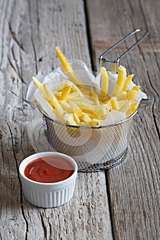 French fries in metal basket with tomato ketchup