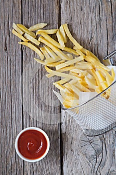 French fries in metal basket with tomato ketchup