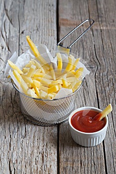 French fries in metal basket with tomato ketchup