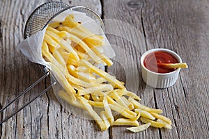 French fries in metal basket with tomato ketchup