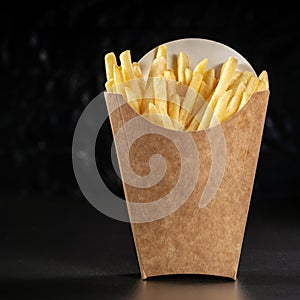 French fries in a paper basket. Fast food.French fries in a paper box on black background, menu food concept.