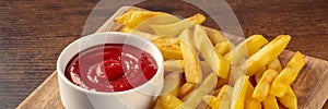 French fries, potato snack with ketchup, fast food on a wooden table