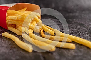 French fries poured out of a bag on a black cement floor