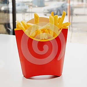 French fries in a red box are on the table in a restaurant