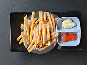 french fries with sauce and mayonnaise on black background. top view