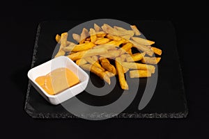 French fries with sauce on wooden background.