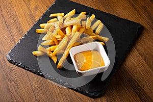 French fries with sauce on wooden background.