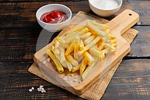 French fries served on cutting board on wooden table