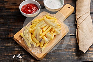 French fries served on cutting board on wooden table