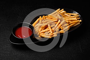 French fries served with ketchup on a black background