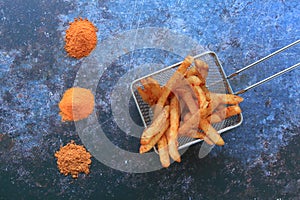 French fries in the stainless basket and barbecue, cheese, paprika powder from top view
