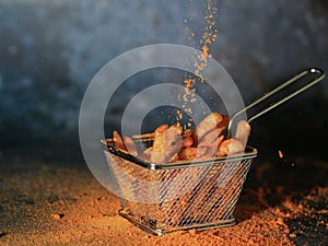 French fries in the stainless basket sprinkled paprika powder
