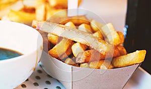 French fries on tracing paper on board on wooden table