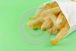 french fries in white paper bag on soft green background. fast food