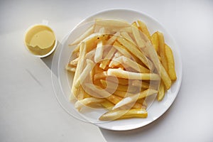 French fries on a white plate with sauce. Delicious fried crispy potatoes