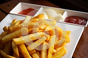 French fries on white plate served with chili, tomato sauce and mayonnaise. Favorite snack of American junk food