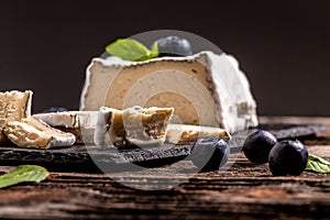 French goat Valencay cheese. Pouligny-Saint-Pierre French cheese with blue mold with berries on a slate board rustic background