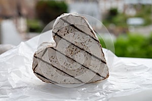 French heartshaped neufchatel cow cheese on white paper and view on old houses of Etretat, Normandy, France