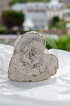 French heartshaped neufchatel cow cheese on white paper and view on old houses of Etretat, Normandy, France