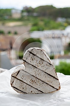 French heartshaped neufchatel cow cheese on white paper and view on old houses of Etretat, Normandy, France